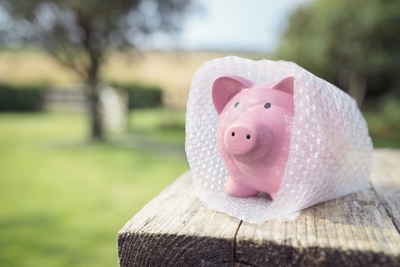 A piggy bank is shielded by bubble wrap, representing the concept of savings protection.