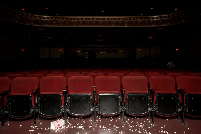 Darkened, empty movie theater with floor littered with popcorn.