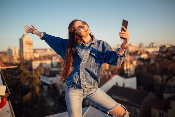 Woman dancing on rooftop with mobile phone