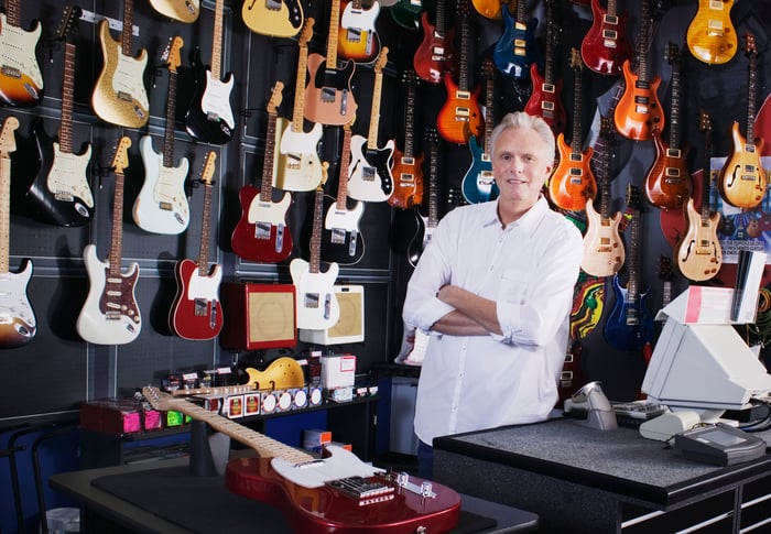 Older man behind cash register at guitar store