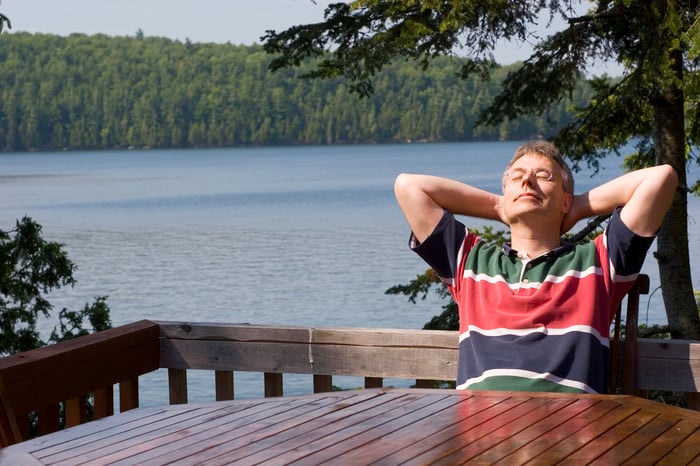 man at a table on a deck by a lake.