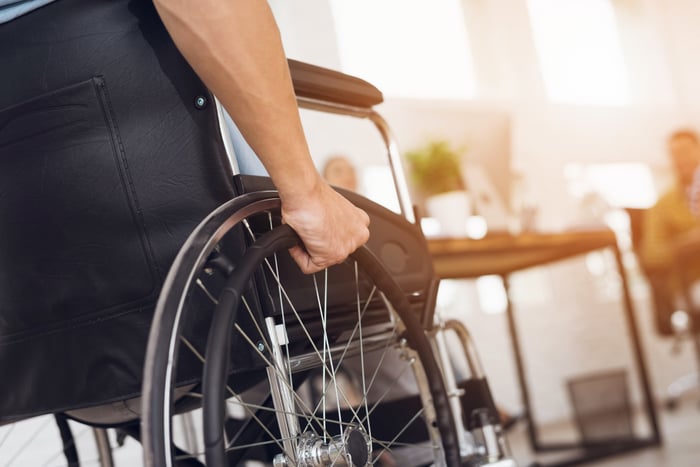 A person pushing the wheel of their wheelchair. 