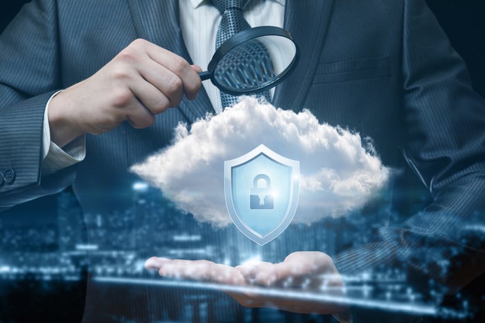 Man is exploring the representation of a cloud-security system with a magnifying glass.