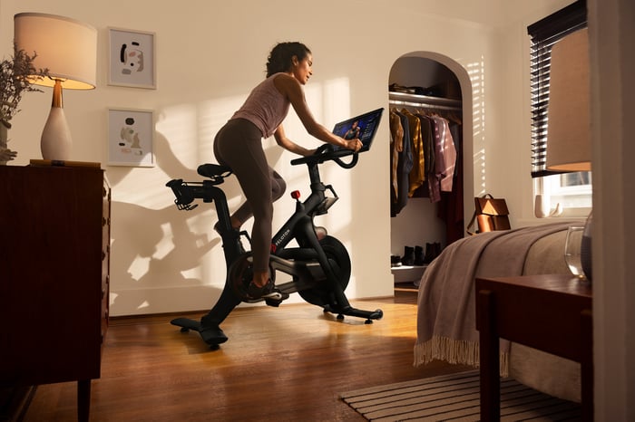 A woman working out with a Peloton in her living room.
