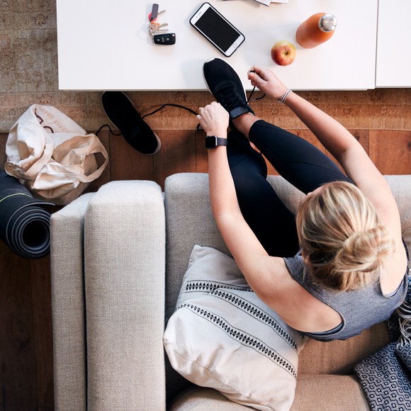 Lady tying shoelaces while sitting on sofa