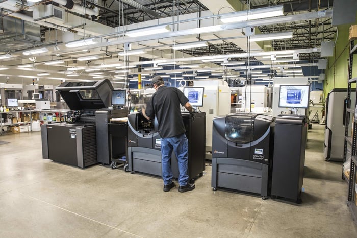 A male machine operator standing in front of a 3D printer.