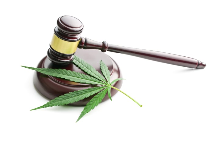 A judge's gavel coming down on a marijuana leaf.