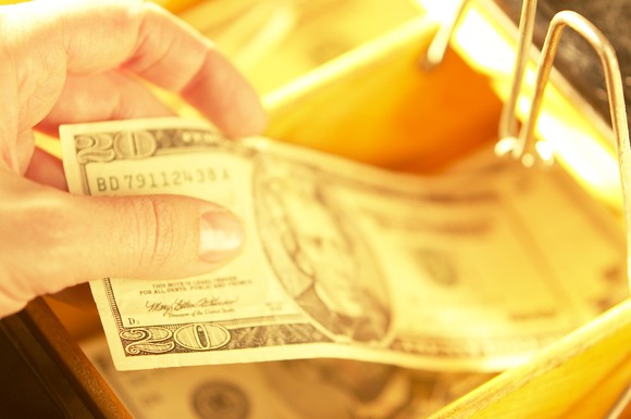 A person holding a twenty-dollar bill.