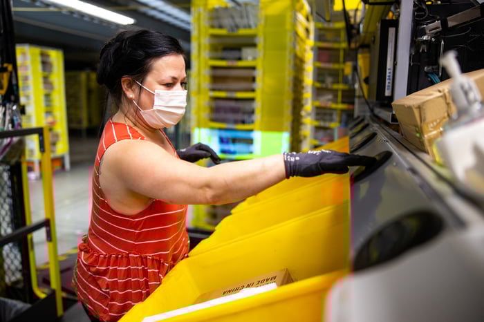 Amazon employee working in a fulfillment center wearing a facemask.