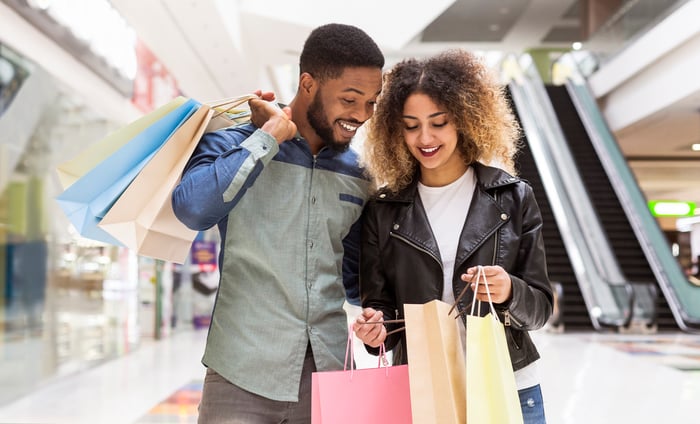 Two people with shopping bags standing in a mall