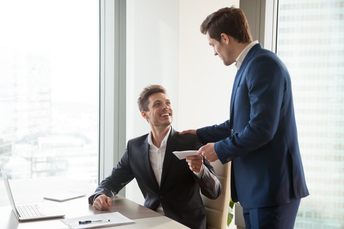 Boss handing employee an envelope