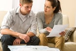 young couple looking over documents looking worried taxes finances