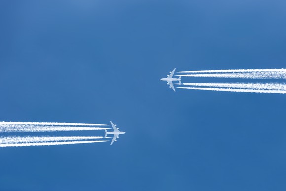 Two planes flying in opposite directions overhead.