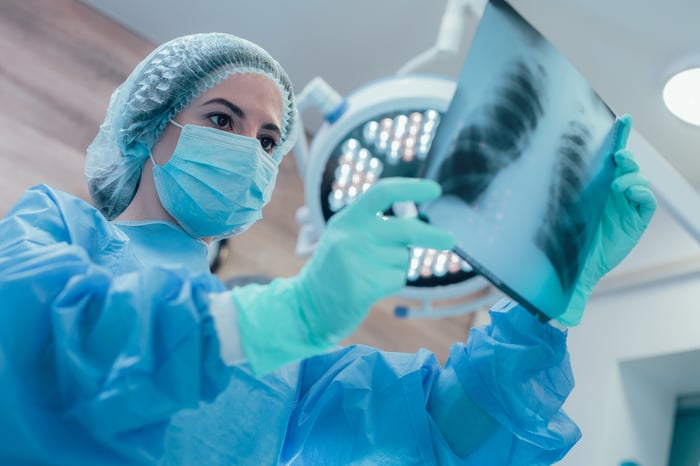 A doctor consults an X-ray image while in an operating room.