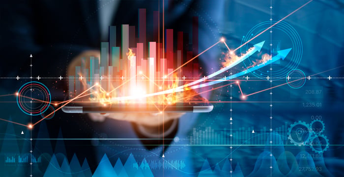 Someone holding a tablet. Charts and other data are illustrated above the screen.