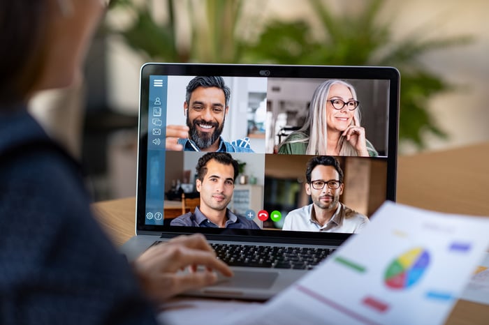 A person on a laptop participating in a video conference with four other people.