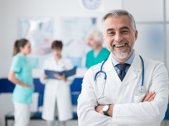 Male healthcare provider standing with his arms crossed while smiling