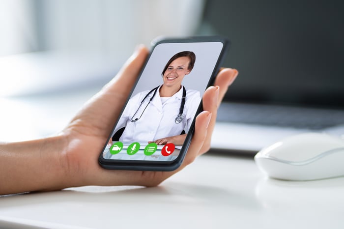 A woman having a video conference with a doctor on a smartphone.