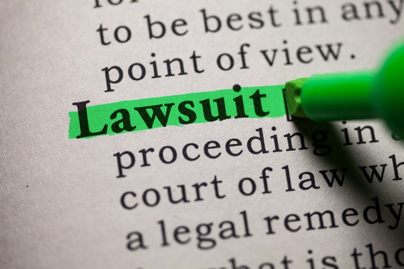A person highlighting in green the word lawsuit in a document.