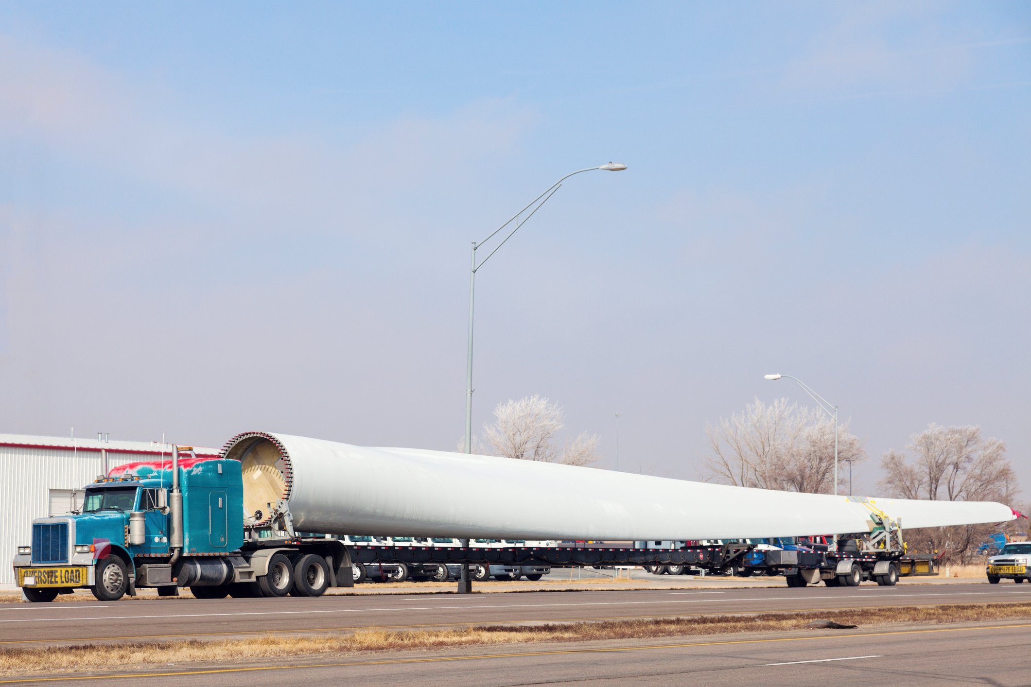 Flatbed truck loaded with a single huge wind turbine blade