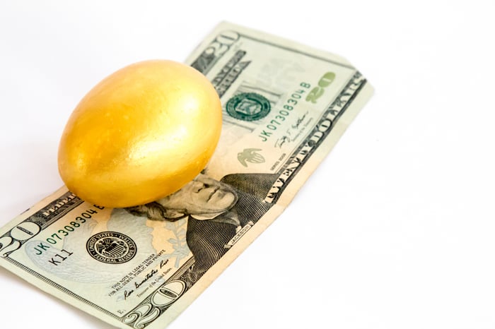 A golden egg on top of a twenty-dollar bill.