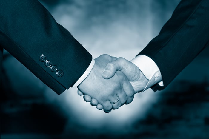 Two businessmen shake hands to signify a merger agreement.