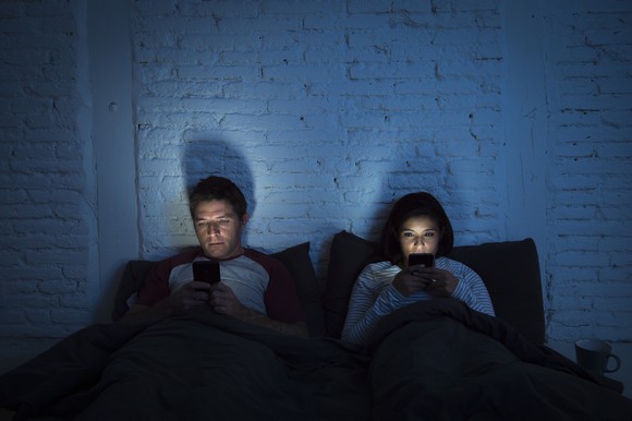 Couple in bed using smartphones