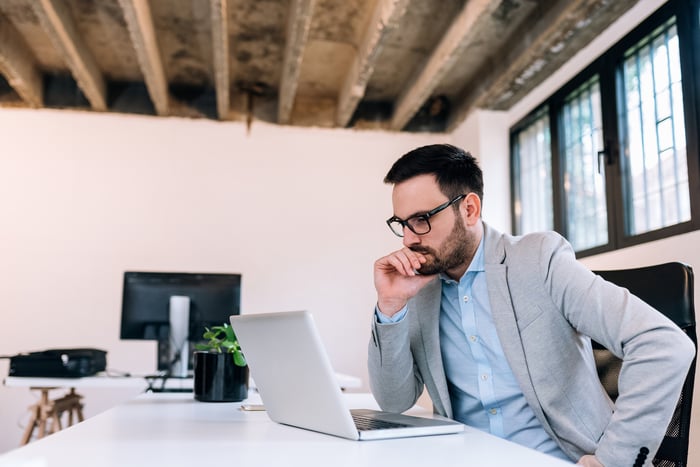 Man in suit staring at laptop deep in thought