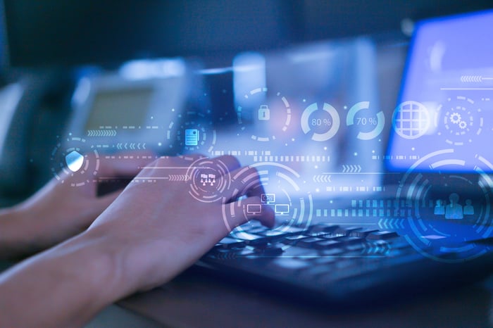 Man's hand typing on a laptop with digital images appearing above.