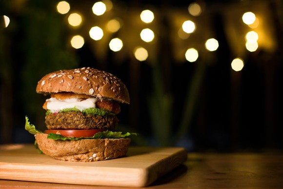 Plant-based burger sitting on a wooden board