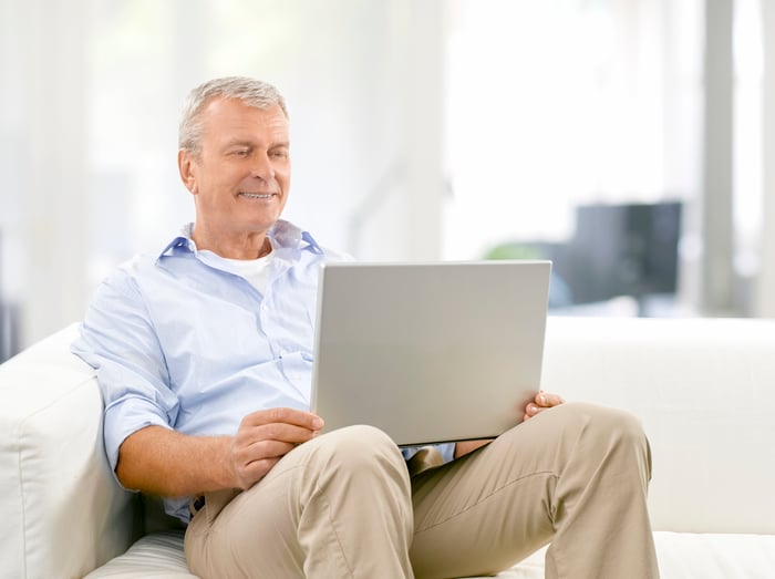 Older man sitting on couch typing on laptop