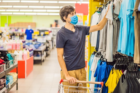 Young man in mask shopping for clothes.