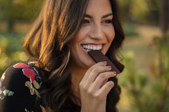 A woman eating a piece of chocolate.
