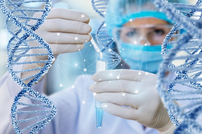 A scientist filing a vial with a dropper with surrounding DNA models.