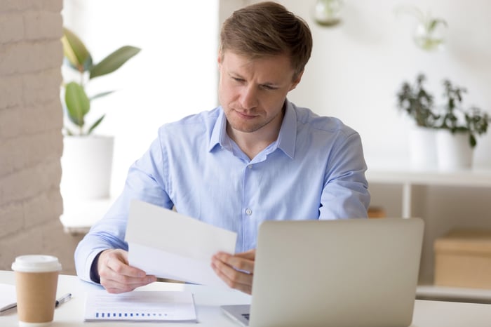 Man at laptop looking at document