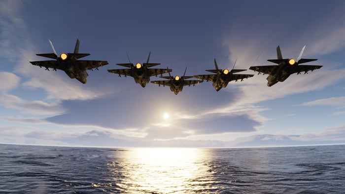 A group of F-35 fighter jets flying over a body of water.