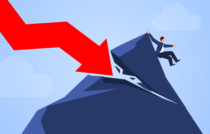 A red charting arrow crashes down on a mountaintop, breaking it and pushing down a businessman.