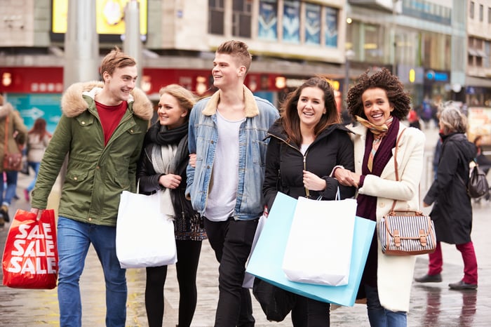 A group of young shoppers walk together holding bags