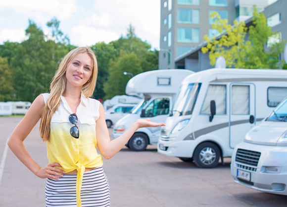 A perky-looking saleswoman in a yellow shirt showing RVs at a dealership.