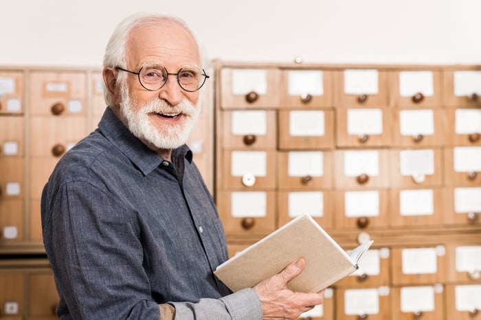 Smiling older person with book in hand.