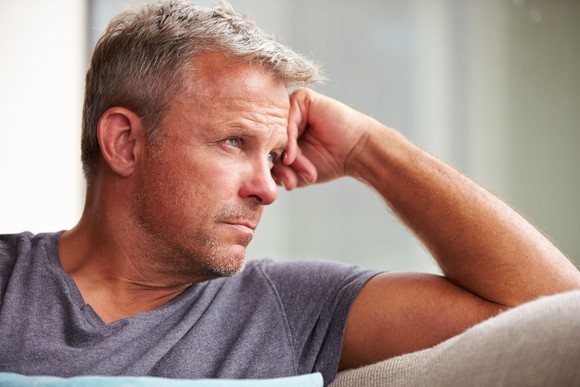 Older man looking out a window with his head resting on his hand