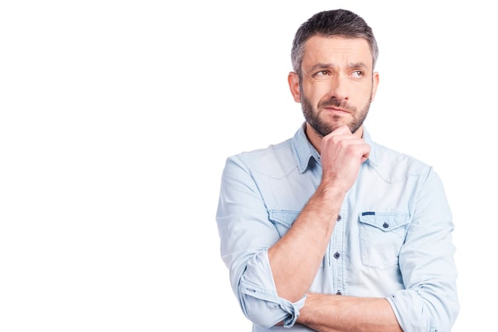 A mature man thinking with his hand on his chin.