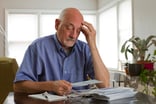 Senior man looking at bills worried -- GettyImages-179813059