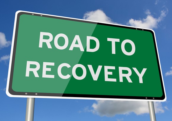 A green highway sign that says "Road to Recovery"