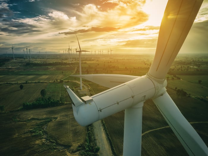 A close-up of a wind turbine with a bright sun in the background.