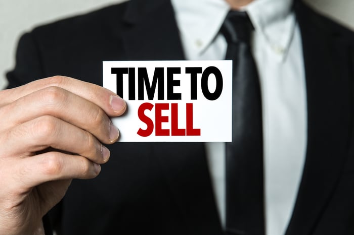 A businessman holds up a sign that says time to sell.