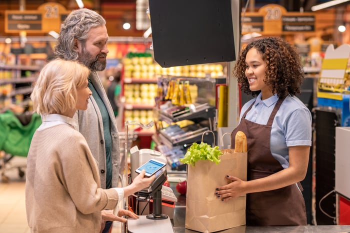 A supermarket employee helping customers in a store.