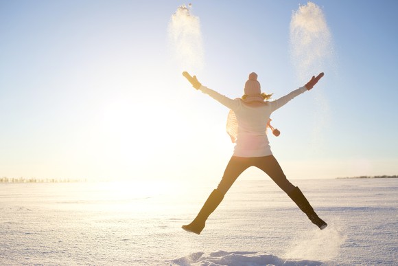 Woman in a winter landscape jumping triumphantly.