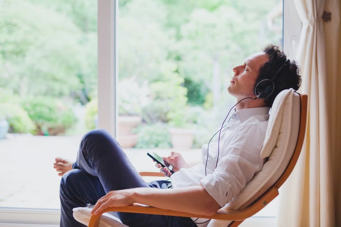 A man sitting in a chair with his eyes closed listening to music with headphones on