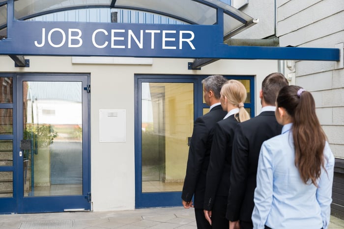 A line of people standing in front of a building labeled job center.